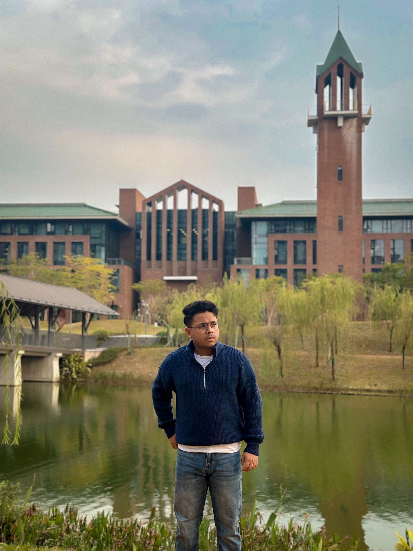Hasnat Jani Rafin seated near a campus clocktower at sunset